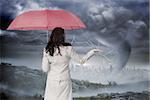 Businesswoman holding umbrella against stormy sky with tornado over cityscape