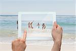 Hand holding tablet pc showing young friends having fun at the beach