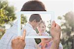 Hand holding tablet pc showing happy couple in the park