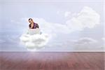 Thinking man sitting on floor using laptop and smiling against clouds in a room