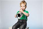 Isolated Young Boy Blowing Trumpet. Early learning and daycare concept