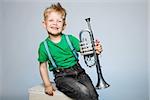 Happy little boy smiling and holding trumpet