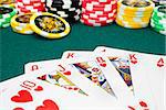 royal flush and unfocused gambling chips of a green fabric background