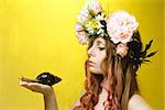 calm pretty girl with snail in hand and flower crown on head on yellow background