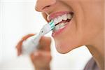 Closeup on young woman brushing teeth