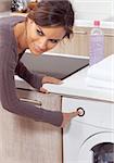 smiling woman pressing a button on her washing machine