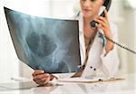 Closeup on medical doctor woman looking on fluorography and talking phone
