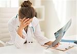 Stressed medical doctor woman with fluorography in office