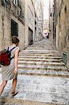 Female tourist walking up stairs, Valletta, Malta