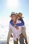 Man piggy-backing woman on beach