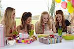 Teenage girl blowing out birthday candles with friends