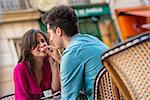 Young couple sharing macaroon at pavement cafe, Paris, France