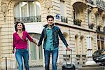 Young couple walking with wheeled suitcase, Paris, France