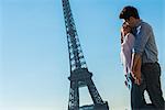 Young couple embracing near Eiffel Tower, Paris, France