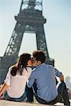 Young couple kissing in front of  Eiffel Tower, Paris, France