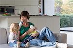 Mother, baby boy and female toddler sitting on sofa