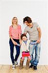 Studio shot of couple with young daughter wearing big boots