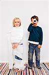 Studio shot of sister and brother with toilet rolls