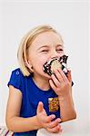 Studio portrait of young girl eating chocolate marshmallow