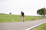 Mature man cycling along country road