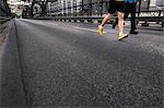 Legs of two men running over city bridge