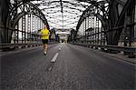 Young male athlete running on bridge