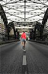 Young female runner crossing bridge