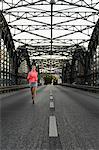 Young female runner across bridge