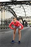 Young female runner preparing for run on bridge