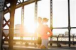 Young male and female running on bridge