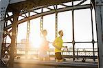 Young male and female running across bridge