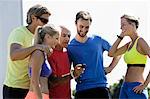 Mature male trainer and a group of adult runners checking stopwatch