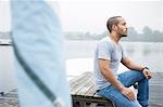 Young man sitting on jetty