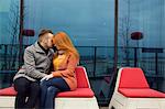 Romantic young couple sitting outdoors on rooftop terrace