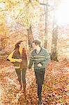 Couple running in forest holding hands