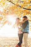 Couple hugging by tree in sunlight