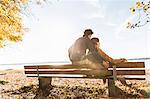 Couple sitting on bench, rear view