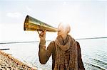 Young woman using megaphone by lake