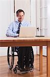 Businessman with spinal cord injury in a wheelchair working on laptop