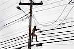 Communications worker on a power pole installing new cable to existing bundles