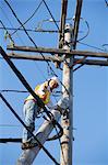 Cable lineman installing new suspension wire from power pole brace