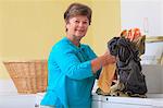 Senior woman doing laundry in a washing machine