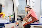 Engineering student wearing protective equipment while working on chemistry experiment in fume hood