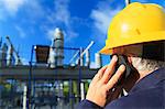 Power engineer talking on a mobile phone at high voltage distribution station, Braintree, Massachusetts, USA