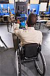 Student in wheelchair studying furnace electronic control system in HVAC classroom