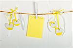 Easter card. Easter decorations and blank note hanging the clothesline on wooden background, painted with white color