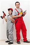 Boy helping his father with some electrical work - standing back to back with tools