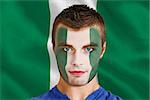 Composite image of serious young nigeria fan with facepaint against digitally generated nigerian national flag