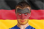Composite image of serious young belgium fan with facepaint against digitally generated german national flag