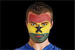 Composite image of serious young ghana fan with facepaint against black